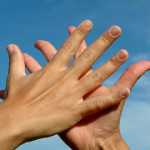 Hands in hands against sky, gesture of friendship concept